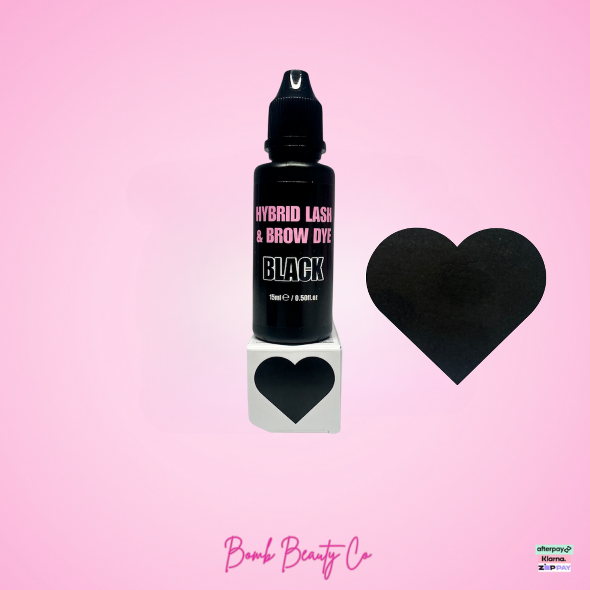 Black bottle of hybrid lash & brow dye with a heart-shaped applicator on a pink background, featuring Bomb Beauty Co branding.