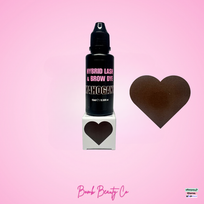 Bottle of hybrid lash and brow dye with a heart-shaped box and heart icon on a pink background, featuring Bomb Beauty Co branding.
